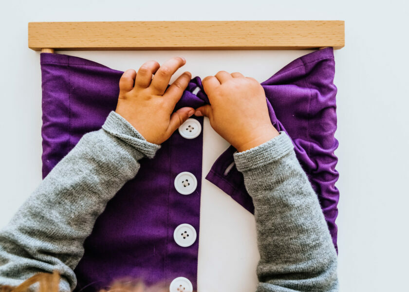 Hand of a student handling montessori material inside a classroo