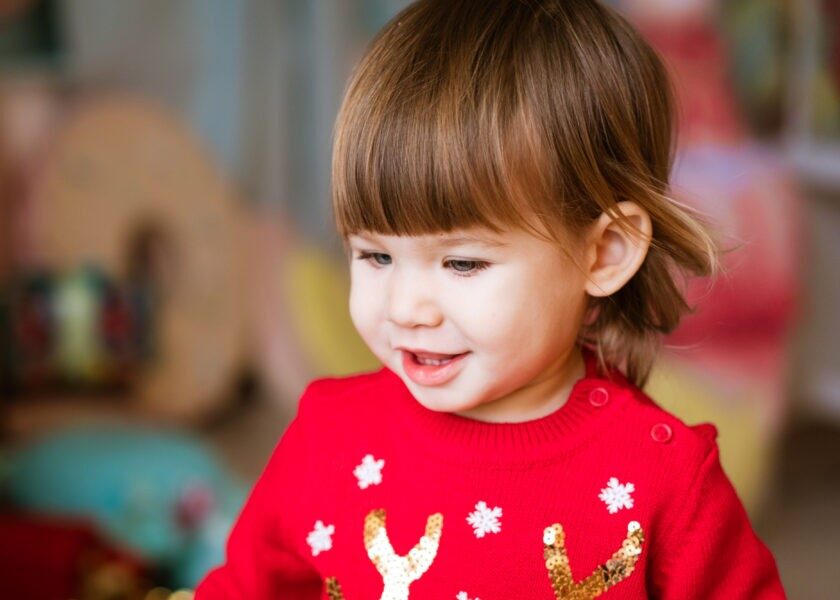 Child close-up portrait of little girl in red sweater. Waiting to receive